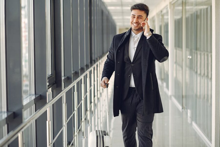 Traveller in a modern hallway holding a suitcase and taking a phone call