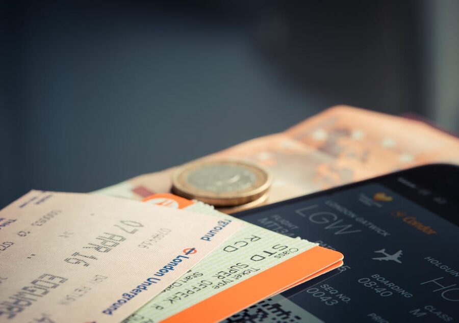 Airline ticket with coins and a smartphone showing flight details