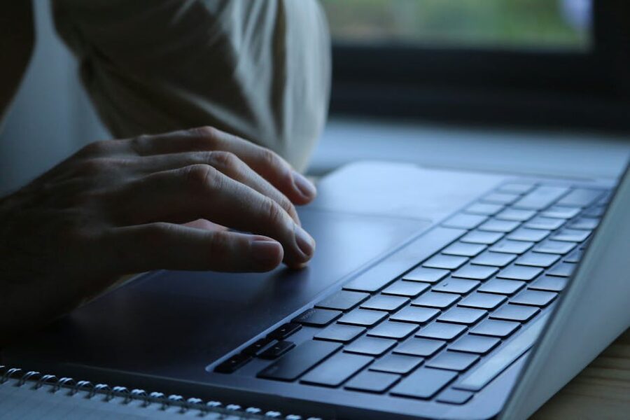Hands typing on a laptop keyboard indoors