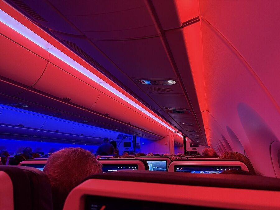 Economy class cabin of an Air France Airbus A350-900 with rows of navy blue seats and mood lighting