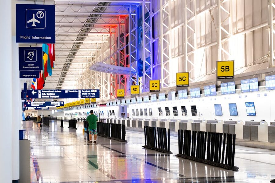 Wide view of a modern airport terminal with rows of check-in counters and overhead signage