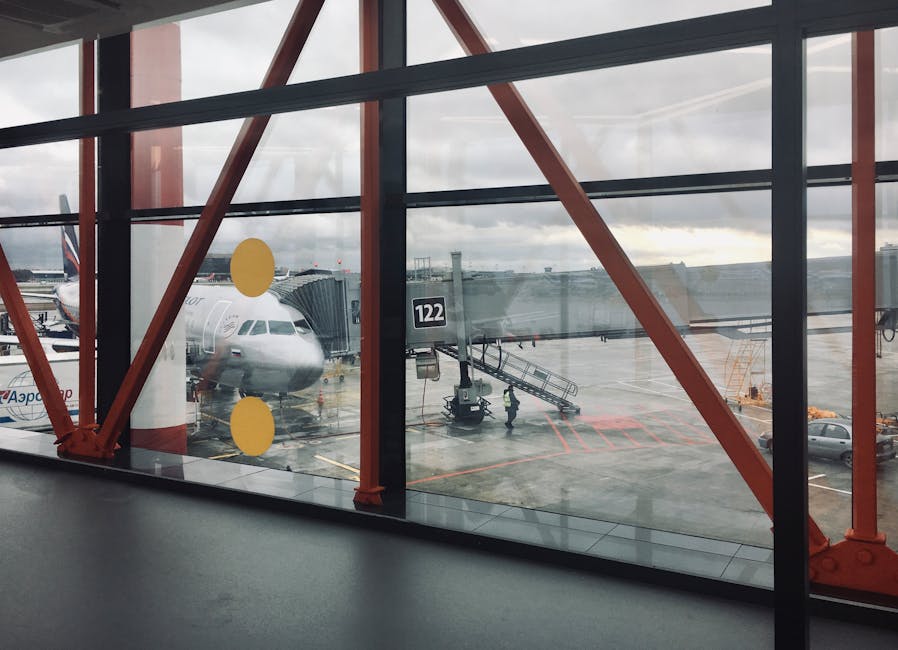 Commercial airplane parked at gate viewed through airport terminal windows