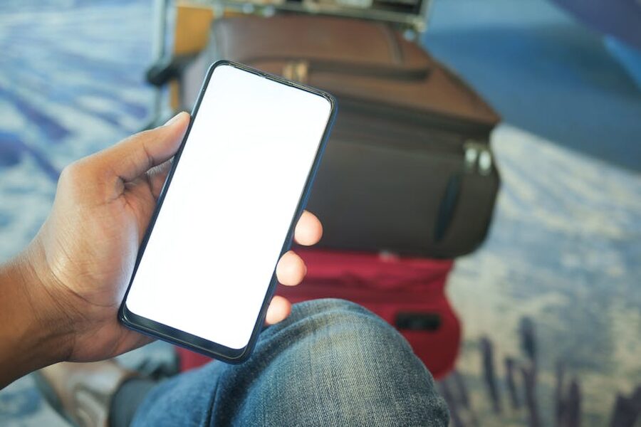 Person holding a smartphone in an airport with luggage visible