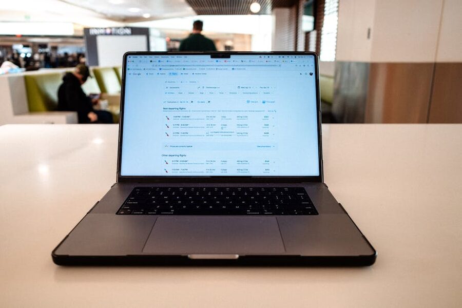 Laptop displaying flight schedules on a table in an airport lounge
