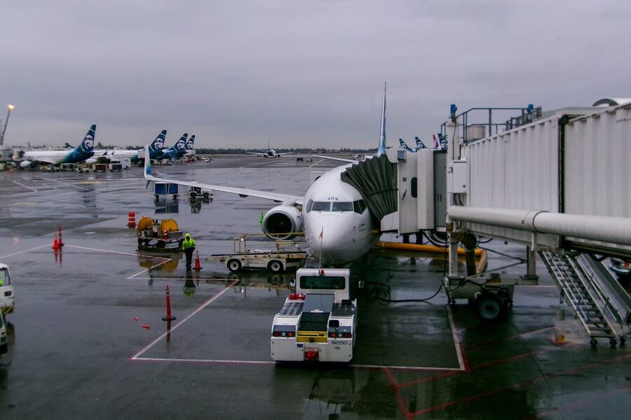 Alaska Airlines passenger airplane parked at SeaTac Airport terminal on a rainy day