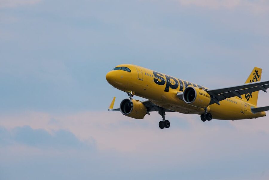 Spirit Airlines yellow Airbus A320 in flight against a clear sky