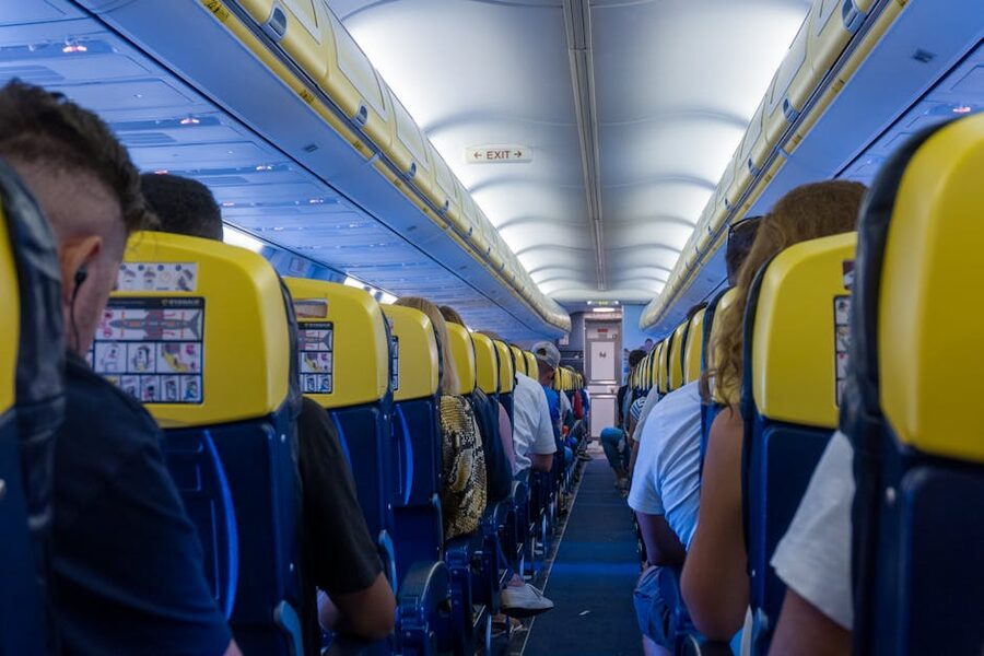 Passengers seated in airplane cabin with yellow seatbacks