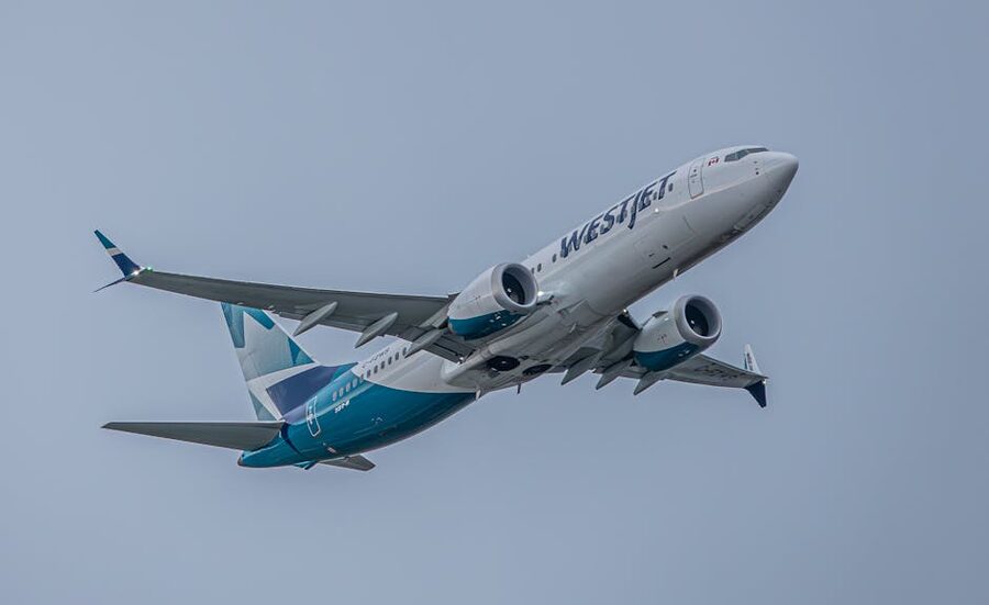 WestJet airplane soaring against blue sky